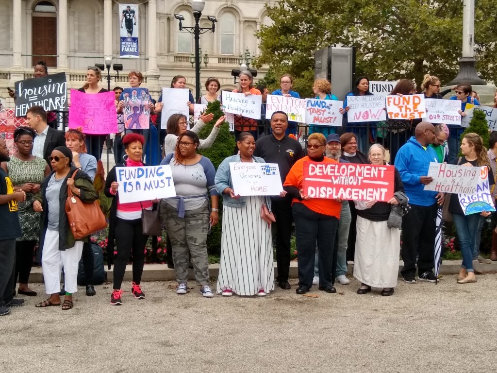 Group of people standing in front of Baltimore City Hall holding signs about funding the Affordable Housing Trust Fund