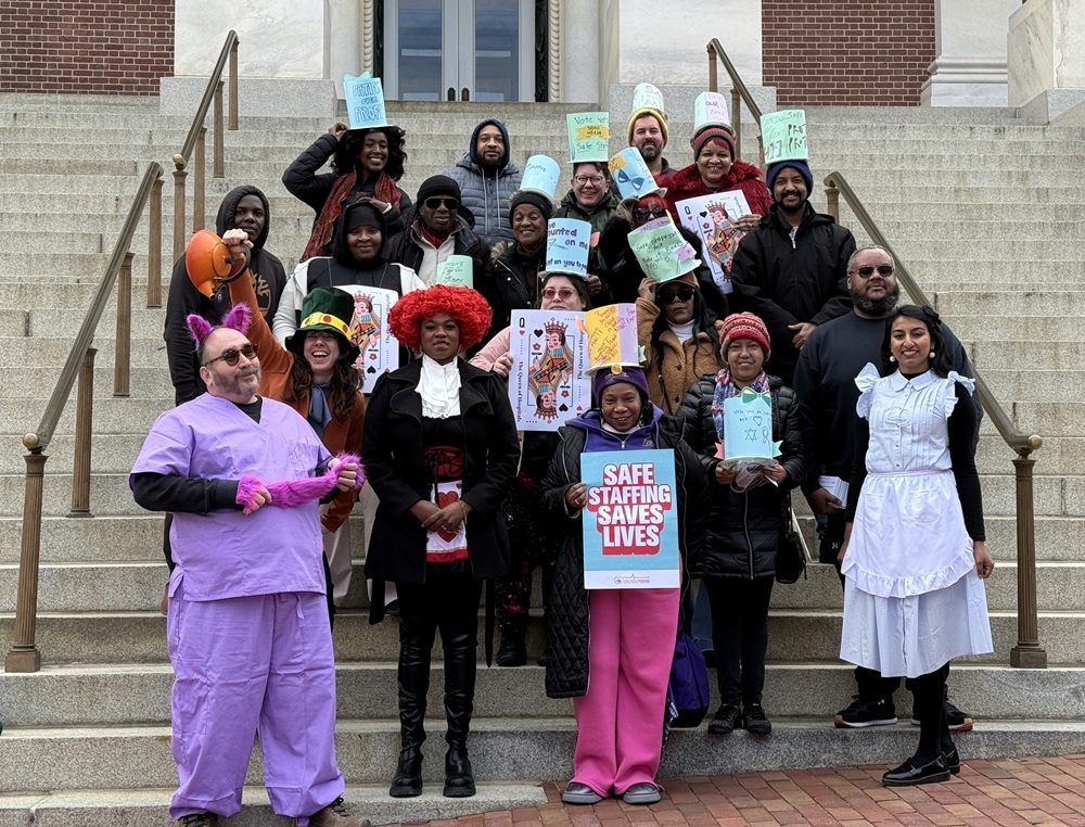 A group of people standing on the steps of the Maryland General Assembly holding signs that say Safe Staffing Saves Lives