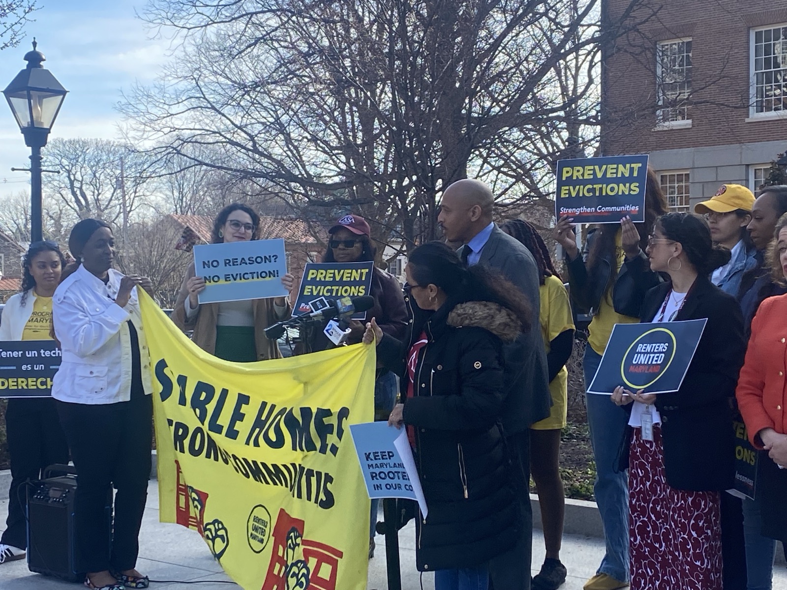 Photo of a press conference with people holding signs that say No Reason? No Eviction; Prevent Evictions; and Renters United Maryland